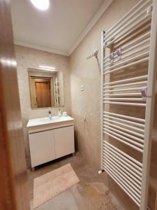 a bathroom with a sink and a mirror and a shower at Chalé Zimbro, Serra da Estrela, Penhas da Saúde in Penhas da Saúde