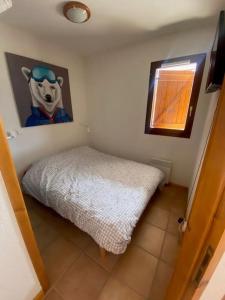 Joue du Loup, appartement F3, pied des pistes في لو ديفولي: غرفة نوم بسرير وصورة بقرة