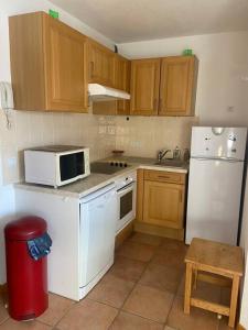 a kitchen with white appliances and wooden cabinets at Joue du Loup, appartement F3, pied des pistes in Le Dévoluy