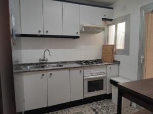 uma cozinha com armários brancos e um lavatório em Feel Welcome Barcelona em Cornellà de Llobregat