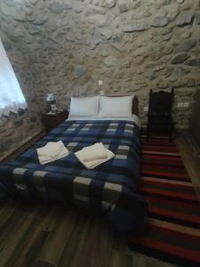 1 dormitorio con 1 cama azul y blanca en una pared de piedra en Ο ΘΟΛΟΣ en Stemnitsa