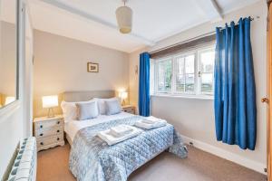 1 dormitorio con 1 cama y una ventana con cortinas azules en East Cottage, en Weymouth