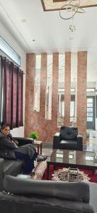 uma pessoa sentada num sofá numa sala de estar em MD Grand Hotel and resort em Agra