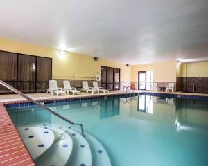 uma grande piscina com cadeiras e mesas brancas em Comfort Inn & Suites em Rogersville