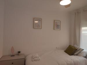 a white bedroom with a bed and a window at Feel Welcome Barcelona in Cornellà de Llobregat