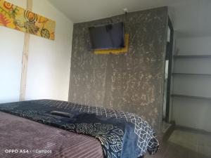 ein Schlafzimmer mit einem Bett und einem TV an der Wand in der Unterkunft CASA BAHAREQUE HOSPEDAJE in Monguí