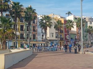 a group of people walking down a street with palm trees at Piso junto al mar de 80m² in Villajoyosa