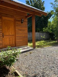 a wooden shed with a door on a gravel driveway at Cabañas Entre Árboles Pucón in Pucón +1 photo