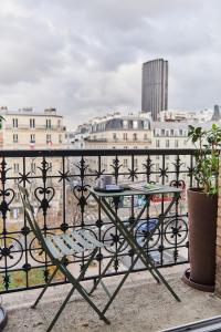 einen Tisch und Stühle auf einem Balkon mit Stadtblick in der Unterkunft Madrigal in Paris