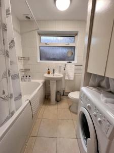 uma casa de banho com um lavatório e uma máquina de lavar roupa em Visit Luton With This 2 BR Rental - Sleeps 6 em Luton