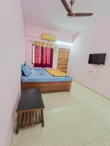 Habitación con cama, mesa y TV. en KIYAN VILLA, en Daman