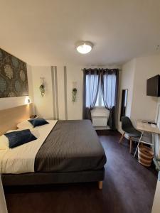 a bedroom with a bed and a desk and window at Hotel Au Bon Sejour in Vitry-le-François