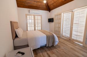 Un dormitorio con una cama con sábanas blancas y techos de madera. en Pousada Mar de Geribá, en Búzios