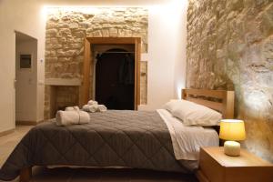 1 dormitorio con cama y pared de piedra en Altemura Suites, en Bari