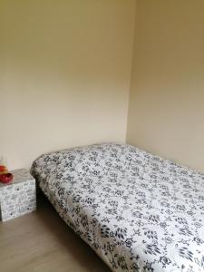 1 dormitorio con 1 cama con edredón blanco y negro en Chambre campagne uxelloise, en Uxeau