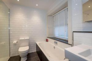 a bathroom with a toilet and a tub and a sink at Lockhart House in St. Andrews