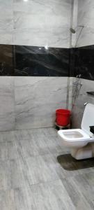 a bathroom with a toilet and a red bucket at Moms Hostel in Agra