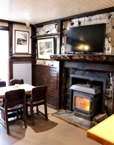 a living room with a fireplace and a table and a television at Tigh an Truish Inn in Oban
