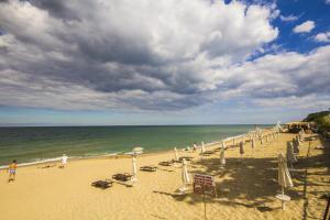 a beach with chairs and umbrellas and the ocean at Coral Guest House in Obzor