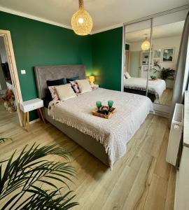 a bedroom with a large bed and a green wall at Przytulna Apartment close to the airport and PKM in Gdańsk