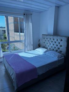 a bed in a bedroom with a large window at Apartamento moderno con balcón - Pitalito Huila in Pitalito