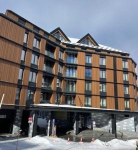 a large brown building with snow in front of it at Woodside Story in Kopaonik