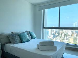 uma cama branca num quarto com uma grande janela em Palmetto sunset 36 em Cartagena das Índias