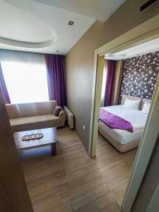 een kleine kamer met een bed en een bank bij Udi Hotel in Canakkale