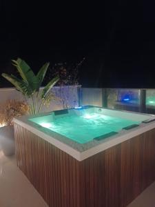a jacuzzi tub in a backyard at night at APTO 107-Pé na Areia Praia do Maceio - 2 suites, 2 banheiros+SPA Jacuzzi+Roupas de cama in São Miguel do Gostoso