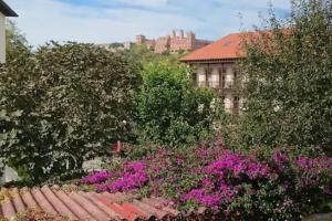 a garden with pink flowers in front of a building at El Balcón de Bolingas in Comillas
