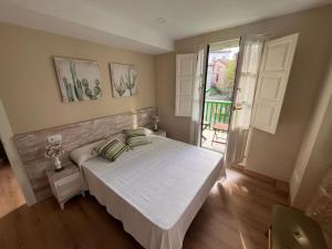 a bedroom with a large white bed and a window at El Balcón de Bolingas in Comillas