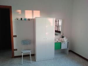 Zimmer mit einem weißen Schrank und einem Stuhl in der Unterkunft Su domus de Corinne in Tratalias