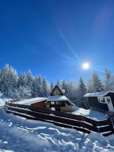 a house covered in snow with the sun in the background at Planinska kuca ANDJELA 1 in Mitrovac