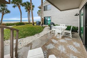 un patio con mesa, sillas y el océano en Beachfront Aldea 13, en Clearwater Beach
