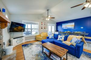 a living room with a blue couch and a tv at Lakefront Eatonton Getaway with Dock and Grill! in Resseaus Crossroads