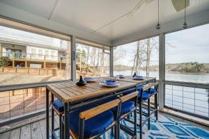 a large screened porch with a wooden table and chairs at Lakefront Eatonton Getaway with Dock and Grill! in Resseaus Crossroads