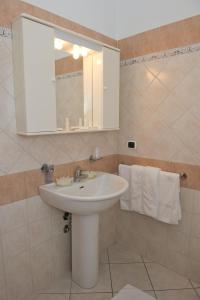 een badkamer met een wastafel, een spiegel en handdoeken bij Residenza Raggio in Riccione