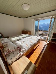 um quarto com uma cama e uma grande janela em Chalet La Louise avec vue imprenable em Crans-Montana