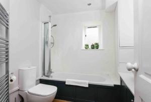 a white bathroom with a tub and a toilet at Beautiful Cotswold Cottage in Rodborough Stroud in Stroud