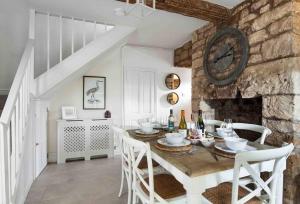 a dining room with a table and a stone wall at Beautiful Cotswold Cottage in Rodborough Stroud in Stroud