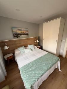 a bedroom with a bed with a green and white blanket at Apartamento Bolingas in Comillas