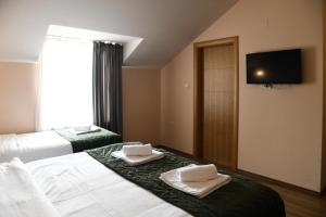 a hotel room with two beds and a flat screen tv at Hotel Garden in Novi Sad