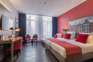 a hotel room with two beds and a desk at Leonardo Hotel Amsterdam City Center in Amsterdam