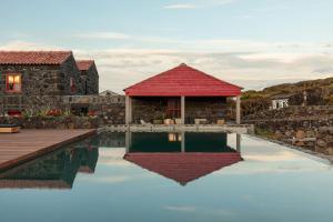 a house with a swimming pool and a red roof at Adega do Fogo in São Roque do Pico