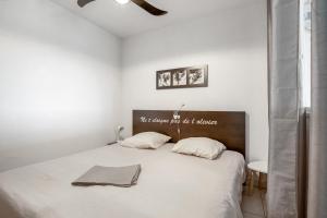 1 dormitorio blanco con 1 cama con 2 almohadas en Jakine - Joli T2 avec terrasse, en Azille