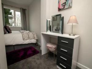 a bedroom with a bed and a dresser with a mirror at Pass the Keys Large Family House near Lincoln in North Hykeham