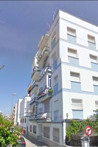 Un edificio blanco con balcones en una calle. en Tierra y Mar, en Sanlúcar de Barrameda