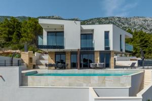 a villa with a swimming pool and a house at Modern villa Luce with sea view in Peljesac in Trstenik