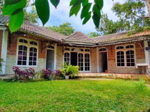a brick house with a lawn in front of it at Sarah's Cottage Toba Samosir in Tuktuk Siadong