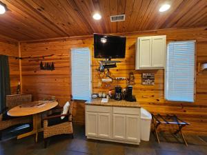 Il comprend une cuisine avec une table et une télévision murale. dans l'établissement Honey Bear Haven Suite 1, à Eureka Springs